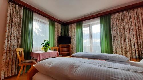a bedroom with green curtains and a bed and a table at Gästehaus Post Aigner in Greifenburg