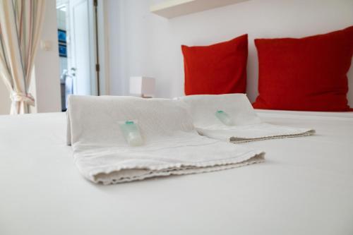 a bed with white towels on it with red pillows at BeGuest Cascais Casa da Tia Marta in Cascais