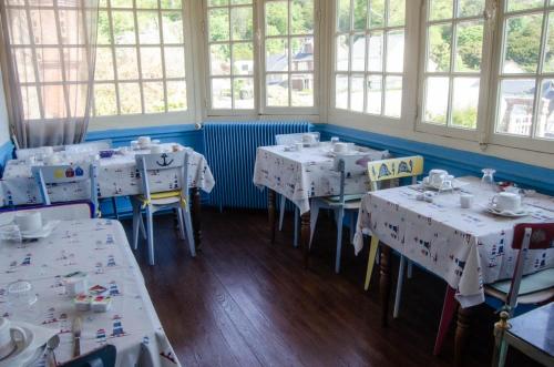 Cette chambre dispose de tables et de chaises blanches ainsi que de fenêtres. dans l'établissement Villa les Dunes, à Saint-Jean-le-Thomas