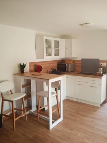a kitchen with white cabinets and a table and chairs at Maison d'hotes - chambre-kitchenette-salle de bain-espace extèrieur in Nîmes
