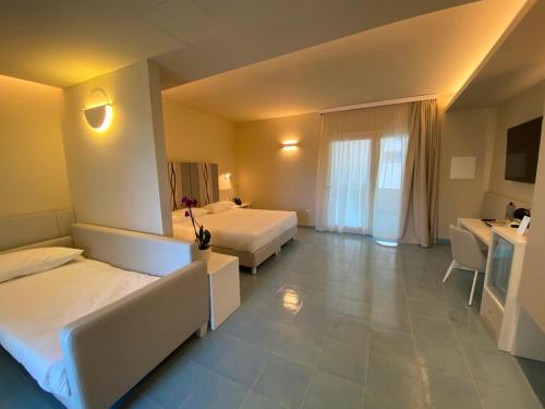 a hotel room with two beds and a bathroom at Hotel Village Eden in Capo Vaticano