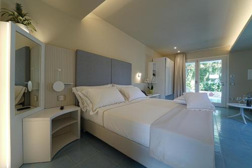 a bedroom with a large white bed and a window at Hotel Village Eden in Capo Vaticano