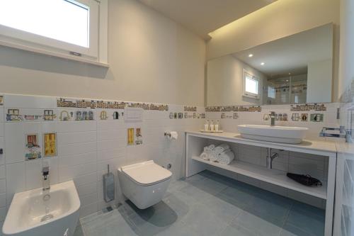 a white bathroom with a toilet and a sink at Hotel Village Eden in Capo Vaticano