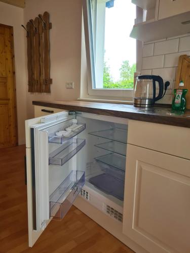 a kitchen with an empty refrigerator with a window at Ferienhuette in Altfriesack