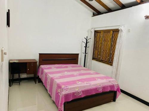 a bedroom with a bed and a desk and a window at Garden Oasis with 1 Bedroom & 1 Bathroom in Batticaloa