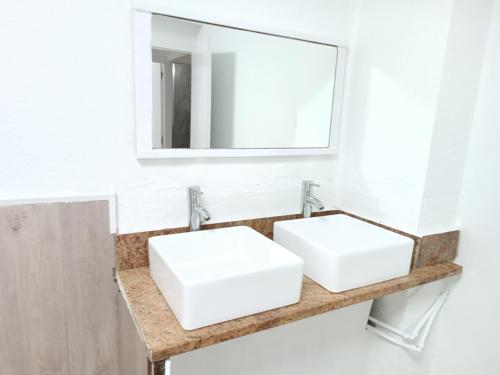 a bathroom with two white sinks and a mirror at Hostel Bretema in Lugo