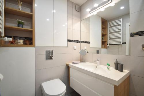 a bathroom with a sink and a toilet and a mirror at Apartament Dobra Energia Kołobrzeg in Kołobrzeg