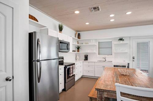 a kitchen with a stainless steel refrigerator and a wooden table at Classy 4BDRM Home W/Pool Mins To Beach and Shops! in Port Aransas
