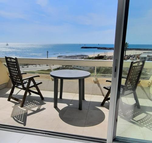 een tafel en 2 stoelen op een balkon met uitzicht op het strand bij Cap d'Agde Naturiste Héliopolis C SEARENA in Cap d'Agde