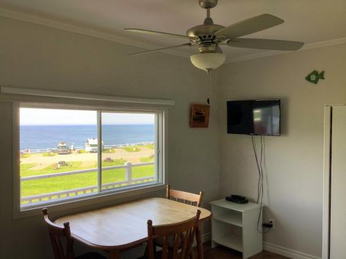 a dining room with a table and a large window at Hôtel-Motel Rocher Percé in Perce