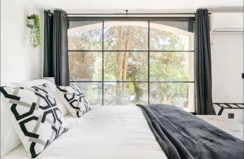 uma cama com almofadas pretas e brancas em frente a uma janela em Suite Bastide Magdaleyna Mougins em Mougins