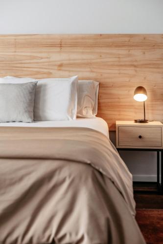 a bed with white sheets and a lamp on a night stand at 5411 Soho Hotel in Buenos Aires