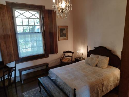 a bedroom with a bed and a window and a chandelier at Fazenda Cachoeira Grande in Vassouras