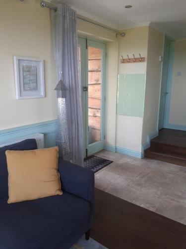 uma sala de estar com um sofá azul e uma porta de vidro deslizante em Distant Lights em Lower Boscaswell