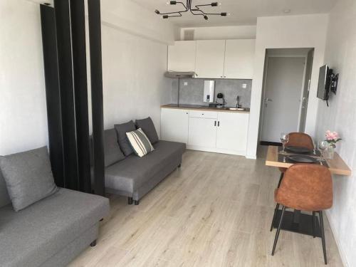 ein Wohnzimmer mit einem Sofa und einem Tisch sowie eine Küche in der Unterkunft Nieuwe studio Westende Edelweiss in Middelkerke