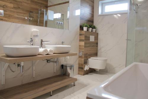 a bathroom with a sink and a tub and a toilet at Penzión a Reštaurácia Harmónia Ostratice in Malé Ostratice