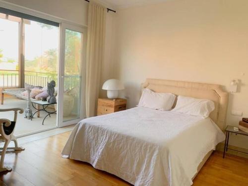 a bedroom with a white bed and a balcony at White shell vilamoura in Maritenda