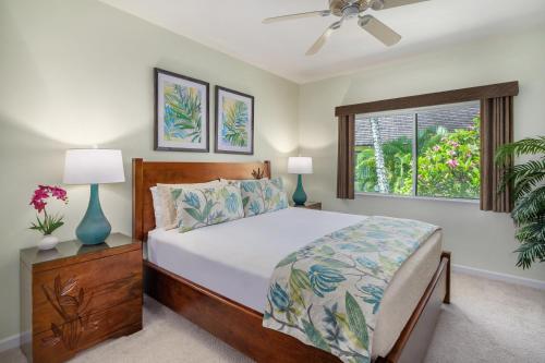 a bedroom with a bed and two lamps and a window at Regency 220 in Koloa