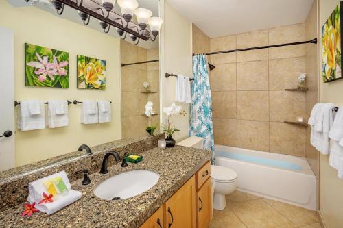 a bathroom with a sink and a toilet and a tub at Regency 220 in Koloa