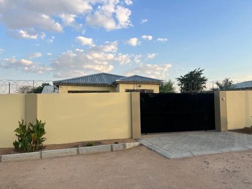 a fence with a black gate in front of a house at Home@Amalia’s in Rundu