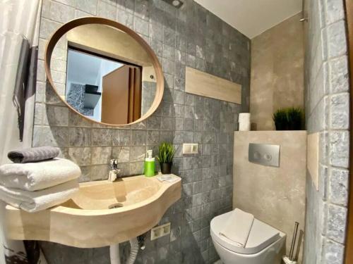 y baño con lavabo, espejo y aseo. en Charming studio shared rooftop terrace/Jacuzzi 360 view, en Budapest