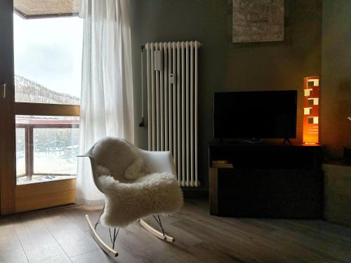 a living room with a white chair and a television at giomein, appartamento di charme artistico ,CIR 0279 in Breuil-Cervinia