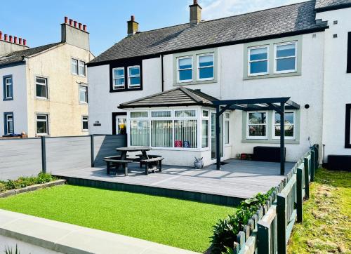 a house with a deck with a picnic table at Beautiful Beach Front Cottage in Allonby