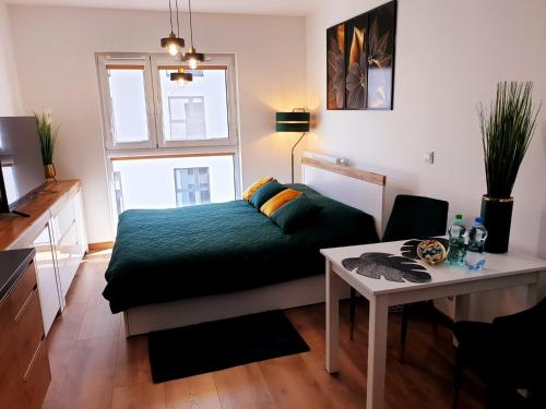 um pequeno quarto com uma cama e uma mesa em Fachpol Apartments Sienkiewicza 22D em Zamość