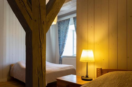Skangaļi的住宿－Skangaļu muiža，一间卧室设有两张床和一张桌子上的台灯。