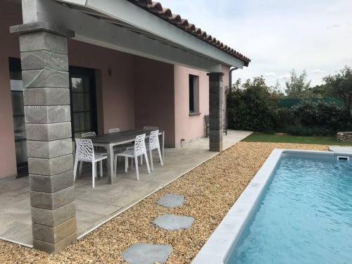 eine Terrasse mit Tisch und Stühlen und ein Swimmingpool in der Unterkunft Villa l'Amoureuse 3 in Saint-Paul-le-Jeune