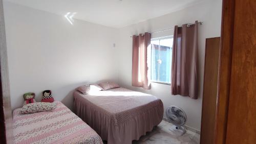 um pequeno quarto com 2 camas e uma janela em Casa Unamar Cabo Frio-RJ em Cabo Frio