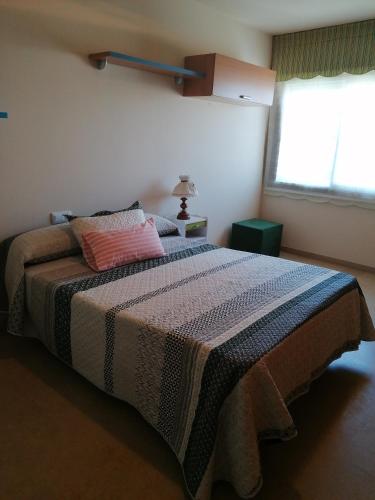 1 dormitorio con 1 cama con manta y ventana en Apartamento Combarro, en Combarro