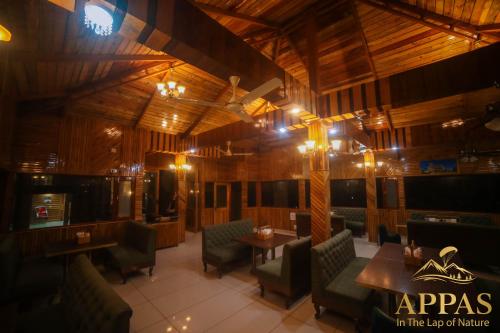 a restaurant with wooden walls and tables and chairs at Appas Hotel in Bīr