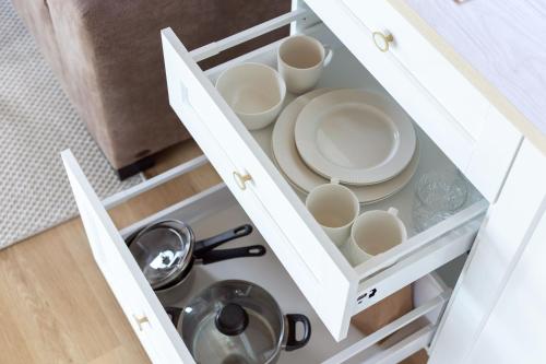 a white cabinet with plates and dishes in it at Pineplace twins NIDA in Žaugėdai