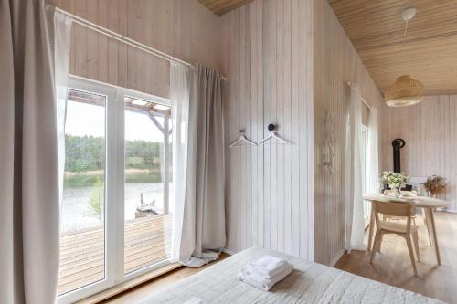 a bedroom with a bed and a large window at Pineplace twins NIDA in Žaugėdai