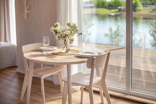 a table with two chairs and a vase with flowers at Pineplace twins NIDA in Žaugėdai