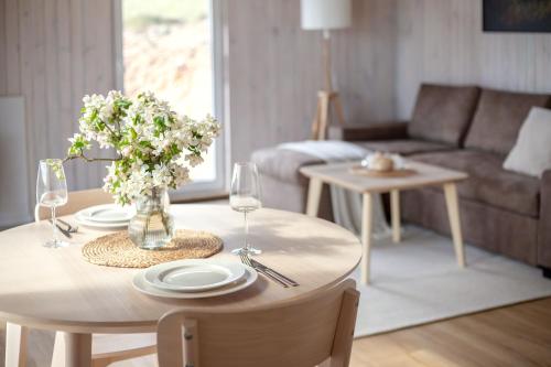 a living room with a table with glasses and flowers on it at Pineplace twins NIDA in Žaugėdai