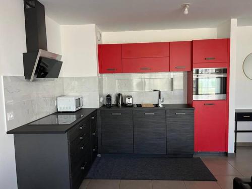 a kitchen with red cabinets and a black counter top at Résidence les Iris - T2 au pied du tram in Annemasse