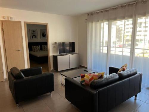 - un salon avec deux canapés noirs dans l'établissement Résidence les Iris - T2 au pied du tram, à Annemasse