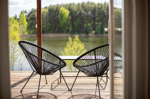 two chairs sitting on a porch with a view of a lake at Pineplace twins NIDA in Žaugėdai