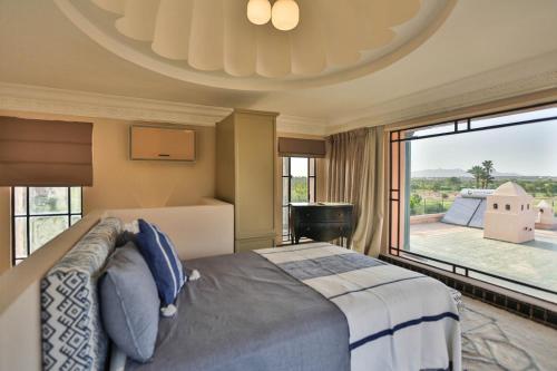 a bedroom with a large bed and a large window at Villa May sur le Golf de la Palmeraie with Cooker and Butler included in Marrakech