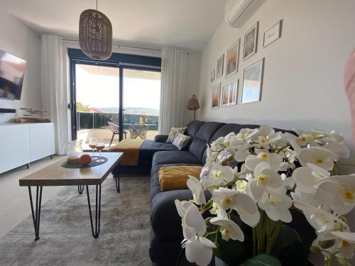 een woonkamer met een bank en een tafel met bloemen bij Apartment Agnes with 63 m2 Rooftop Terrace, Grill and Pool in Okrug Gornji