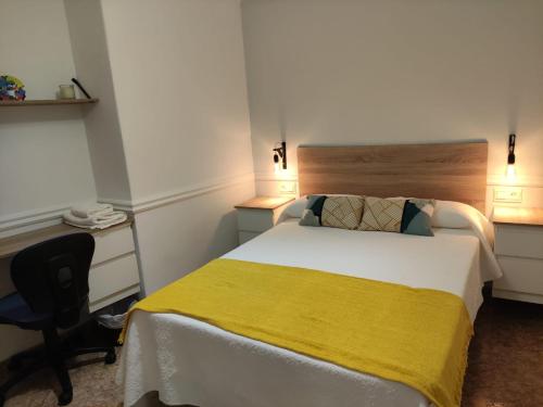 1 dormitorio con 1 cama con manta amarilla y escritorio en LA DESCALZA, en Lucena