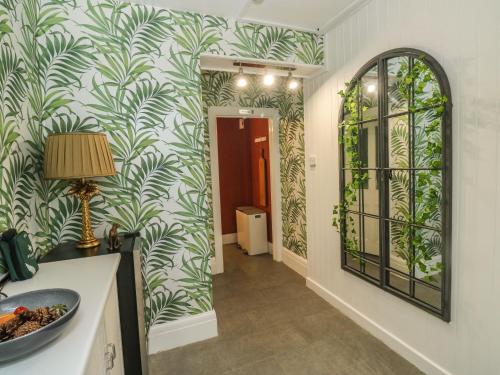 Un pasillo con papel pintado verde y blanco y un espejo. en Russell House, en Paignton