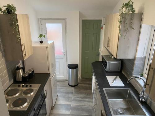 a small kitchen with a sink and a stove at Overhill 3 bedroom flat 5 beds, free parking, ideal for Contractors in Gateshead