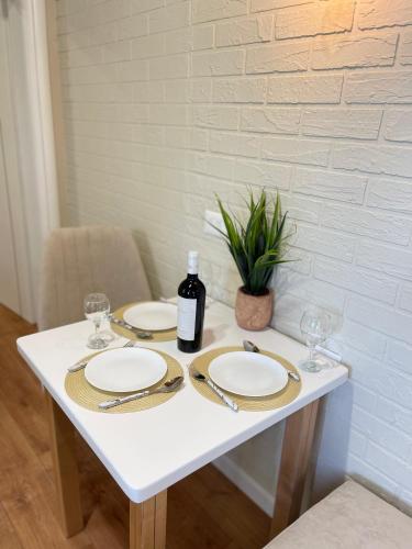 a white table with two plates and a bottle of wine at Arial Penthouse Suites in Vlorë