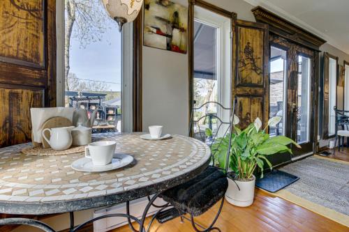 a table and chairs in a room with a balcony at Le petit Manoir Spa et Vue sur rivière St Maurice in Grandes-Piles