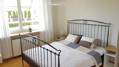 ein Schlafzimmer mit einem schwarzen Bett mit weißer Bettwäsche und einem Fenster in der Unterkunft Błękitny Domek in Wydminy