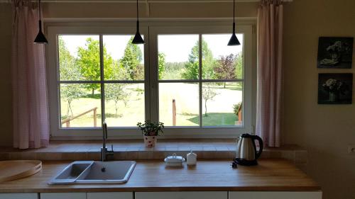 a kitchen with a sink and a large window at Błękitny Domek in Wydminy