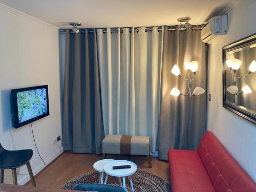 a living room with a red couch and a tv at M-Montt Providencia Apartamentos Amoblados in Santiago